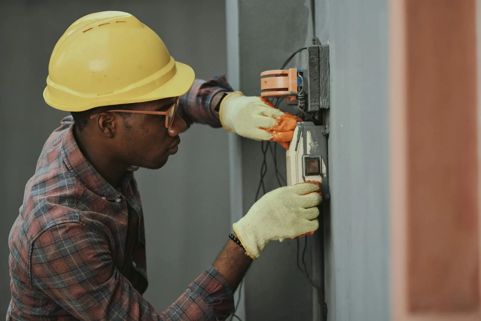 An electrician in a yellow hard hat installing wiring