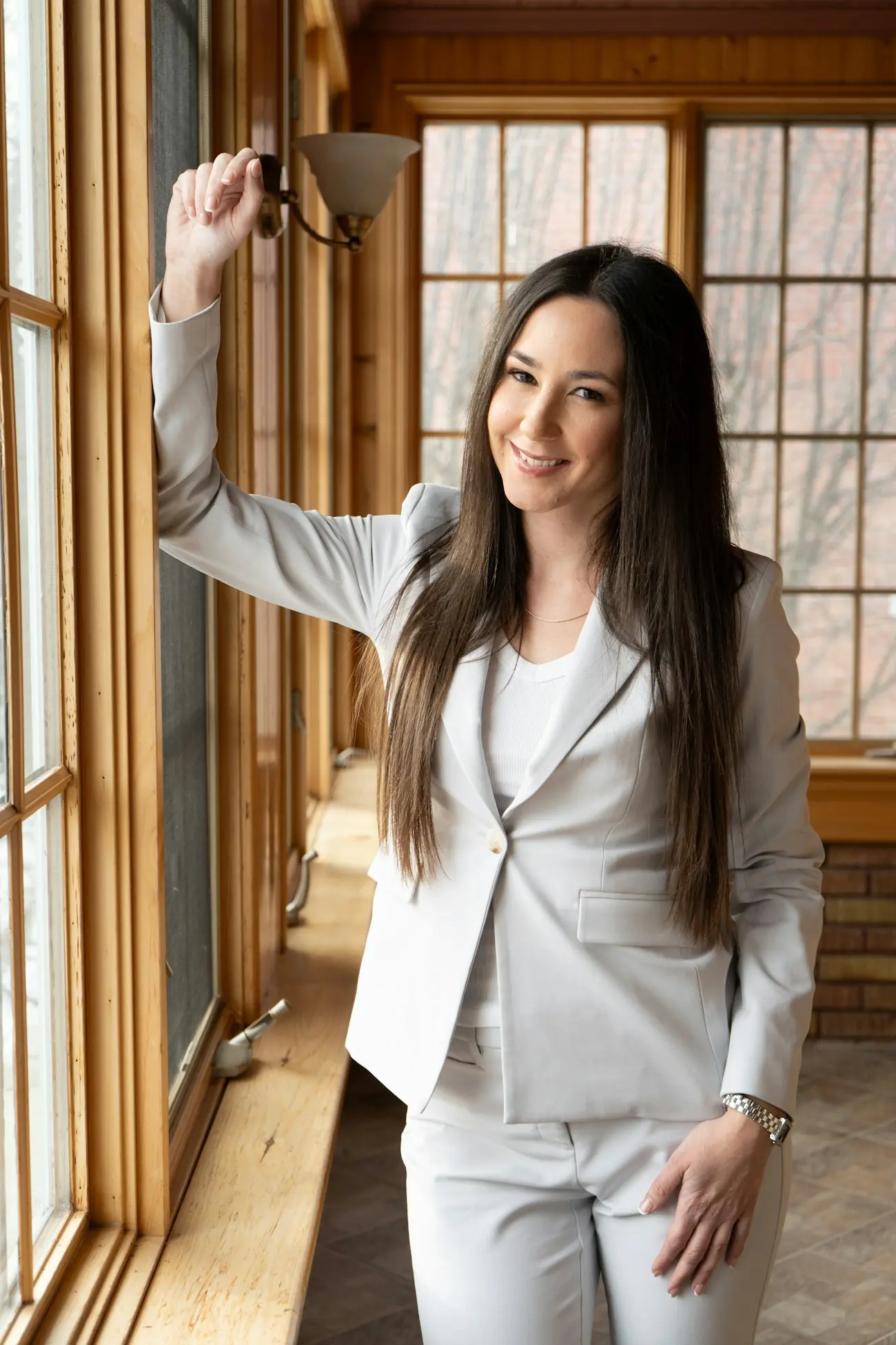 A smiling agent in a grey suit by a window