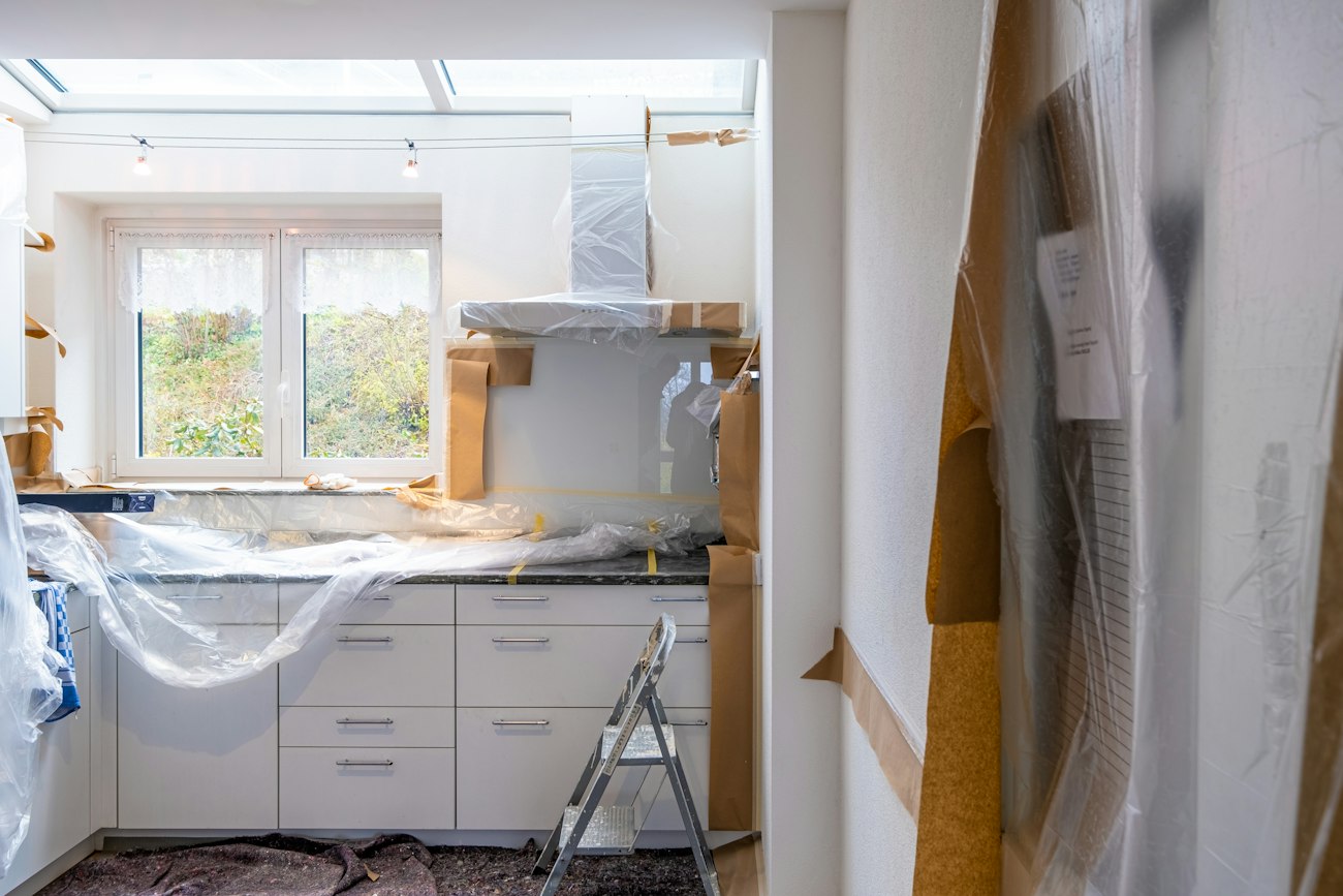 A kitchen under renovation with cabinets covered in plastic